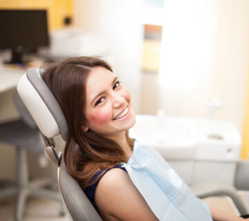 Smiling woman sitting in a dental chair during a checkup.