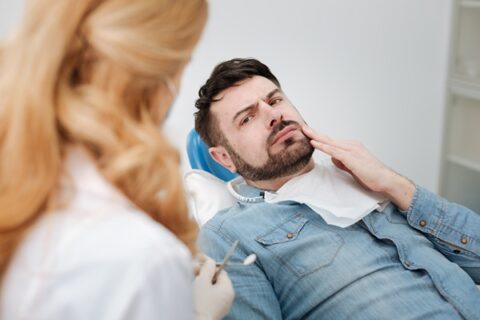 Man at dentist holding his cheek.
