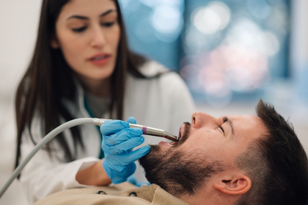 Dentist examining patient's teeth with tool.
