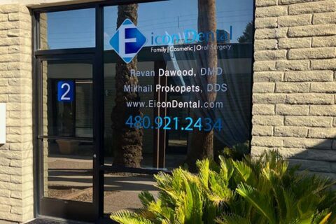 Dental office window with contact info and logo.