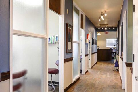 Modern medical clinic hallway with exam rooms and seating.