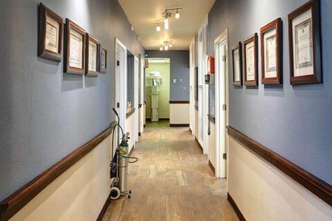 Clean, well-lit hospital hallway with framed pictures and medical equipment.