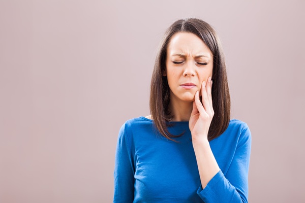 Woman experiencing toothache, holding her cheek.
